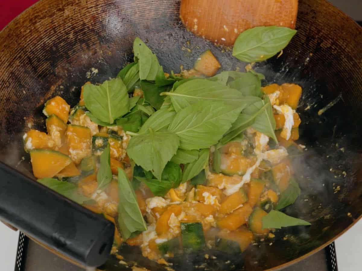 a wok with kabocha squash, eggs and thai basil