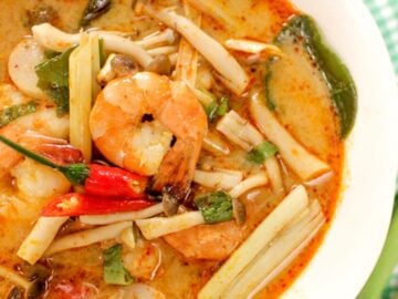 a bowl of tom yum soup with shrimp, mushrooms, lemongrass and chilies
