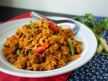 A plate of tuna stir fried in red curry with red and green chilies.