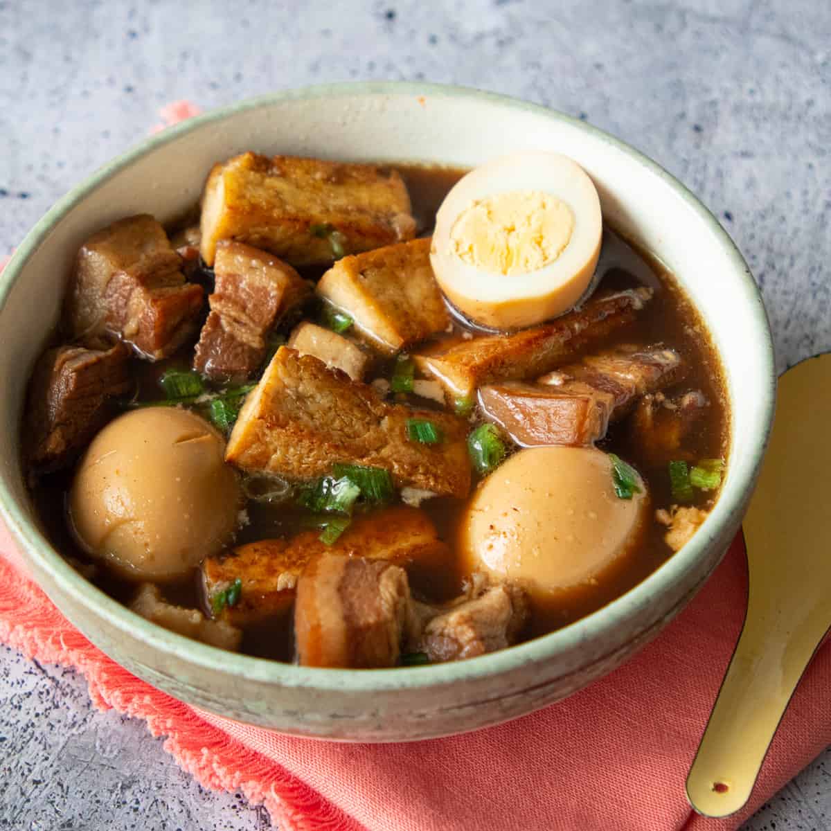 a bowl of thai five spice pork belly and egg stew on an orange napkin