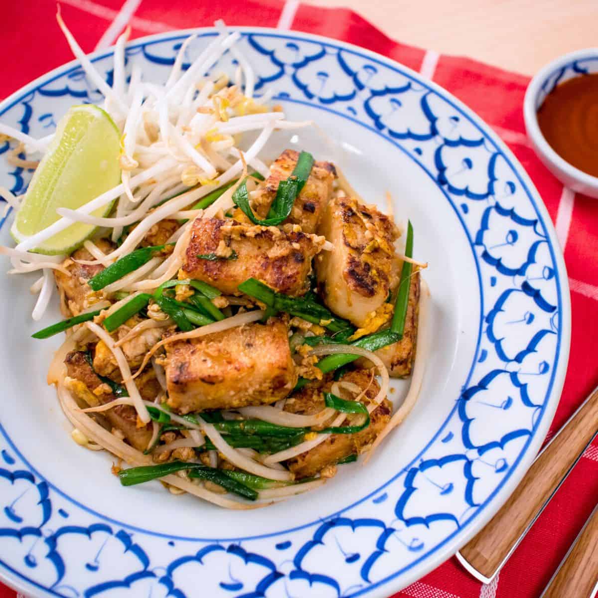 a plate of kanom pakkad with a lime wedge and beansprouts on the side