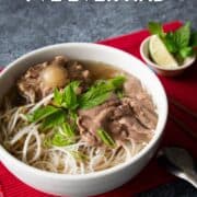 a bowl of oxtail pho with lime wedges and thai bail on the side. Text overlay: THe Best Pho I've Ever Had and hot-thai-kitchen.com