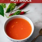 A bowl of prik nam som with text overlay "Thailand's Favorite 2-ingredient hot sauce" and a small spoon and Thai chilies beside the bowl.