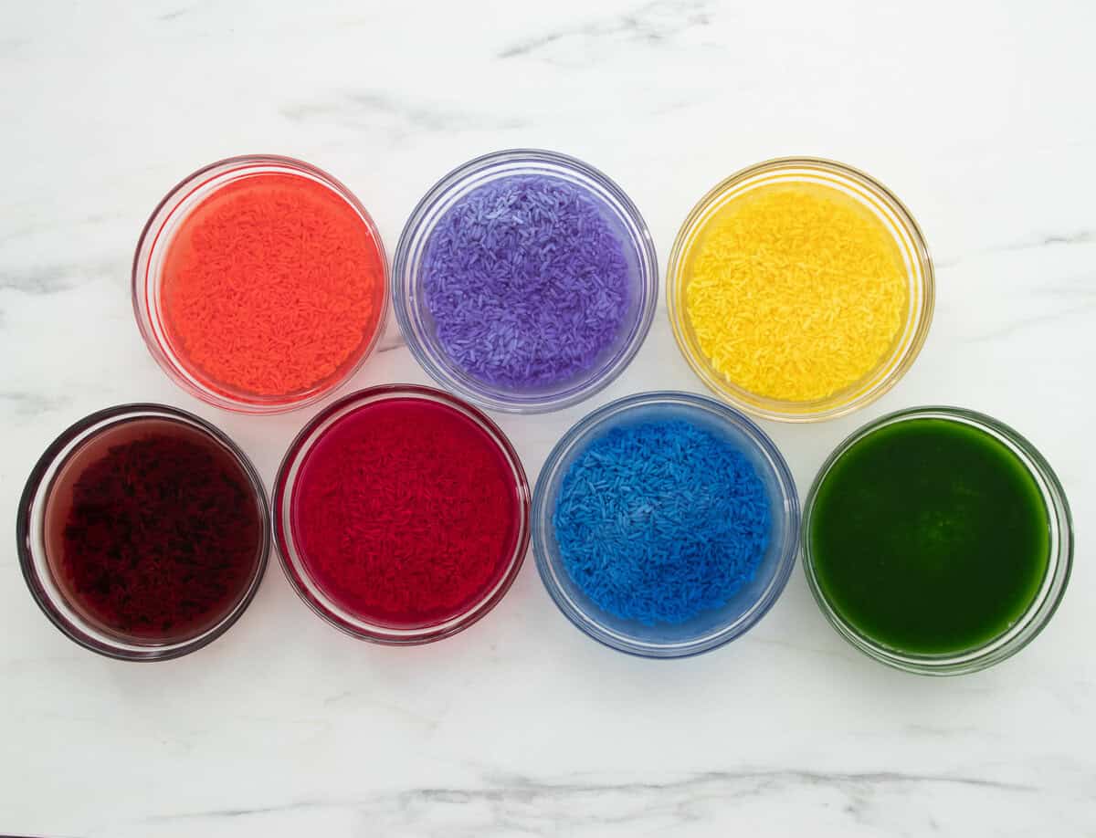 7 bowls of rice soaking in 7 different coloured water