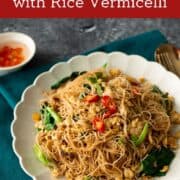 A plate of pad see ew with rice vermicelli with a side of chili vinegar, with text overlay "pad see ew with rice vermicelli"
