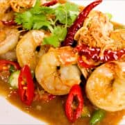 A plate of tamarind shrimp with chlies and cilantro garnish