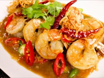 A plate of tamarind shrimp with chlies and cilantro garnish