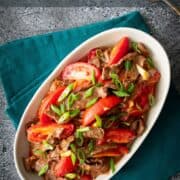 A plate of tomato beef stir fry with text overlay "Chinese tomato beef stir fry" and "hotthaikitchen.com"