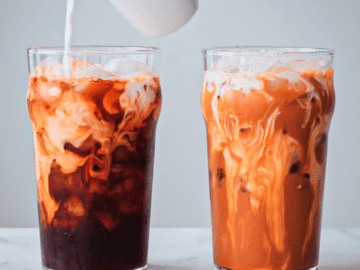 Two glasses of Thai tea, one with half and half being poured into it.